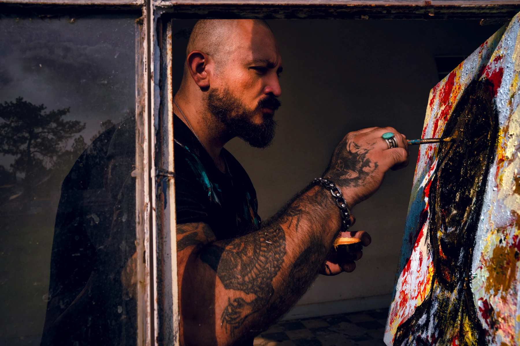 Raul Armando Prieto carefully painting details on a textured, brightly colored canvas.